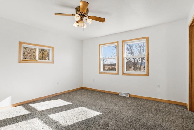 carpeted empty room with visible vents, ceiling fan, and baseboards