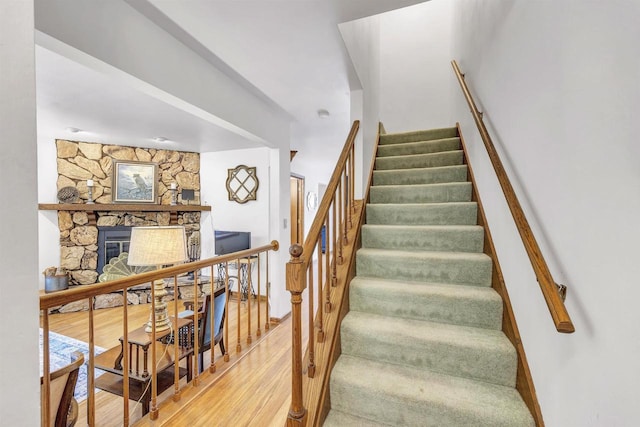 staircase featuring a fireplace and hardwood / wood-style flooring