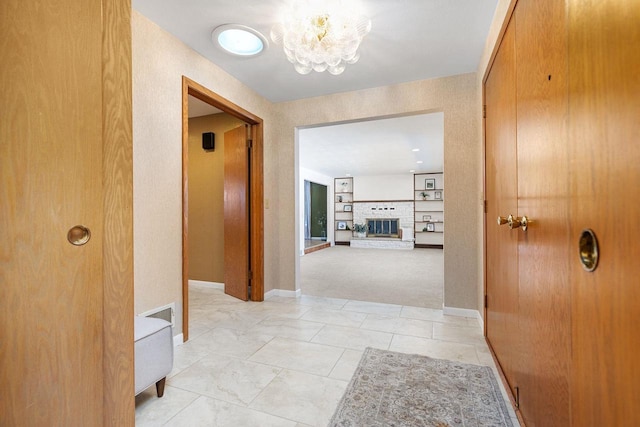 hallway with a notable chandelier, light carpet, and built in shelves