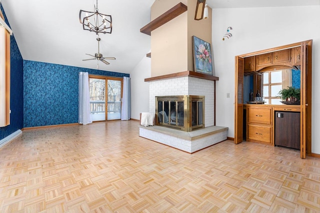 unfurnished living room with ceiling fan with notable chandelier, a fireplace, high vaulted ceiling, and light parquet floors