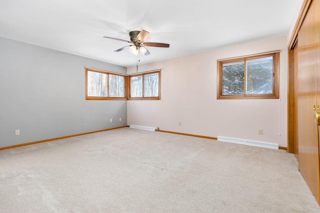 unfurnished room featuring ceiling fan, light carpet, a wealth of natural light, and a baseboard radiator