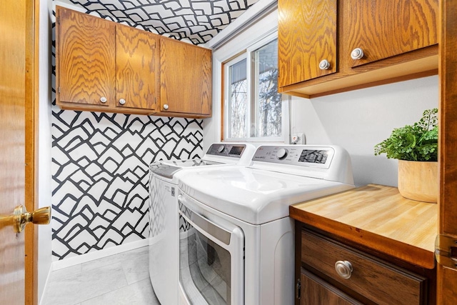 clothes washing area featuring cabinets, light tile patterned floors, and washing machine and dryer