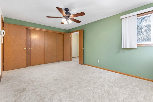 unfurnished bedroom featuring ceiling fan, a closet, and light carpet