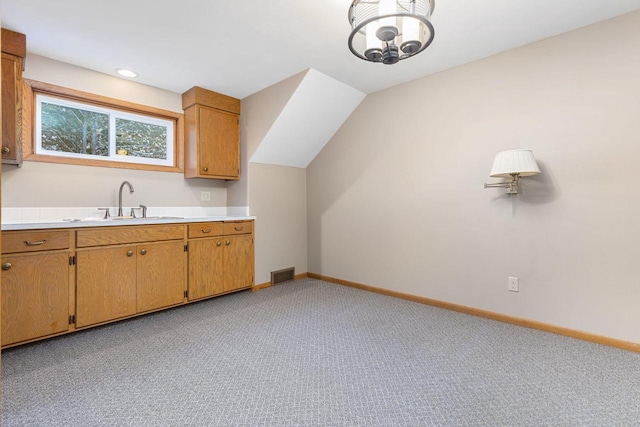 kitchen with a notable chandelier, light colored carpet, lofted ceiling, and sink