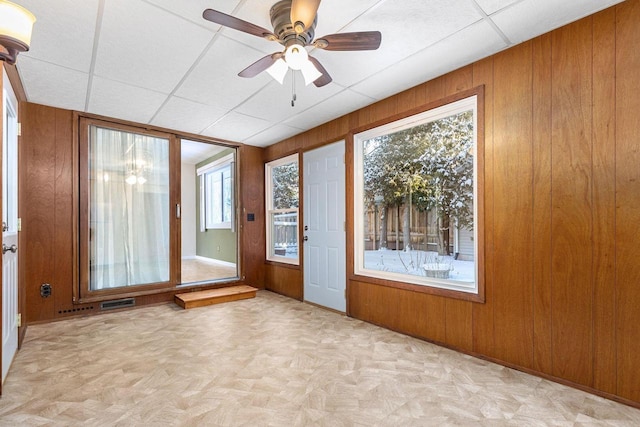 unfurnished sunroom with ceiling fan and a drop ceiling