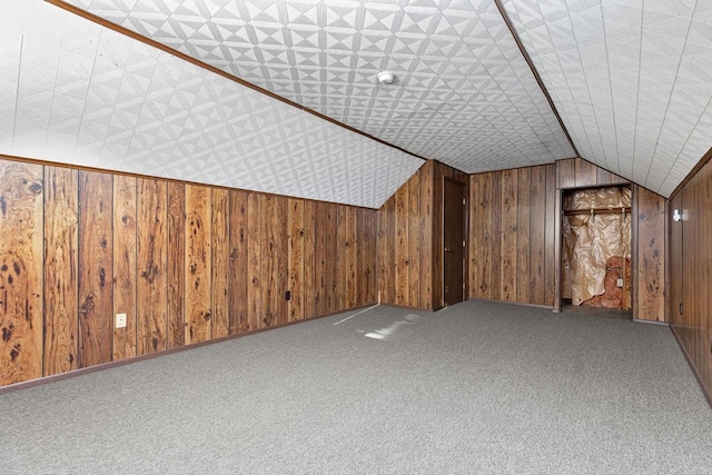 bonus room with wooden walls, carpet floors, and vaulted ceiling