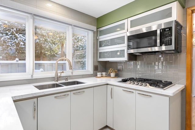 kitchen featuring white cabinets, sink, appliances with stainless steel finishes, tasteful backsplash, and light stone counters