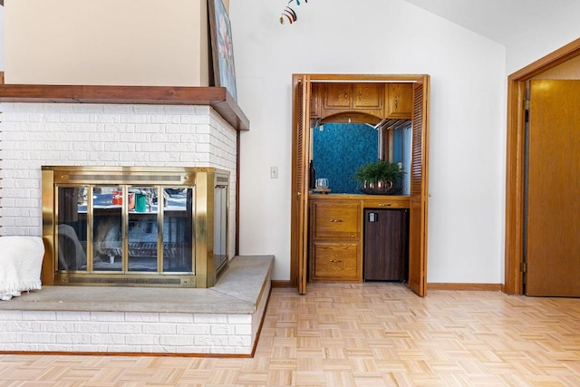 interior space featuring light parquet flooring, vaulted ceiling, and a brick fireplace