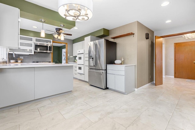 kitchen featuring white cabinetry, sink, hanging light fixtures, stainless steel appliances, and decorative backsplash