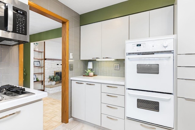 kitchen with white cabinets, decorative backsplash, and white appliances