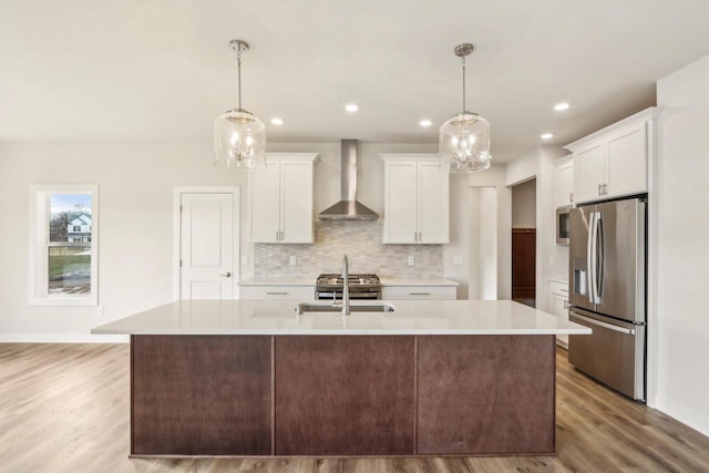 kitchen featuring white cabinets, hanging light fixtures, wall chimney exhaust hood, and appliances with stainless steel finishes