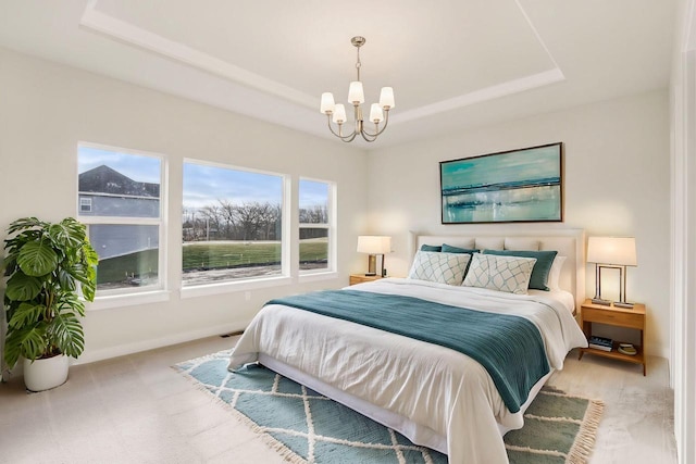 bedroom featuring an inviting chandelier and a raised ceiling