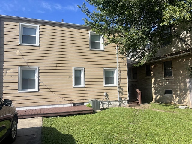 rear view of house with a wooden deck, cooling unit, and a lawn