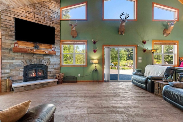 living room featuring a stone fireplace, high vaulted ceiling, a healthy amount of sunlight, and hardwood / wood-style flooring