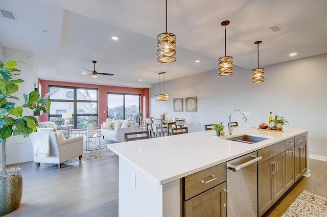 kitchen featuring pendant lighting, a center island with sink, sink, ceiling fan, and light hardwood / wood-style floors