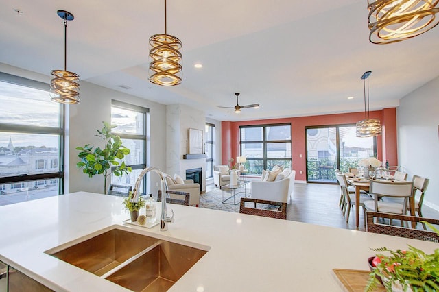 kitchen with ceiling fan, wood-type flooring, sink, and hanging light fixtures