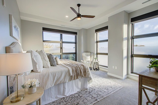 bedroom with light carpet and a tray ceiling