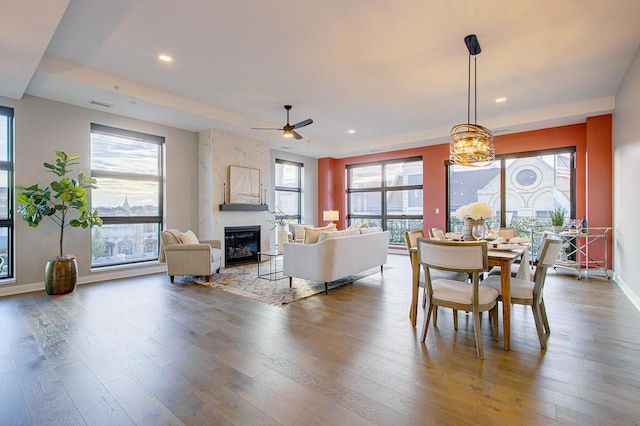 dining space featuring ceiling fan, a fireplace, and wood-type flooring