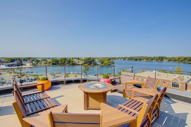 wooden terrace with a fire pit, a patio area, and a water view