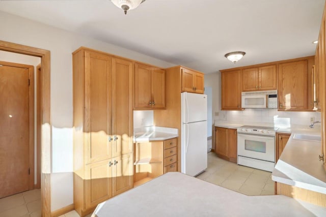 kitchen with backsplash, white appliances, and sink