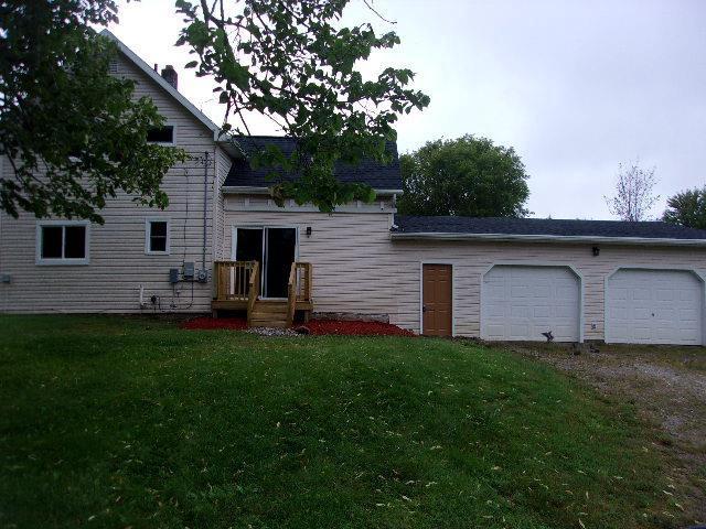 rear view of property featuring a lawn and a garage