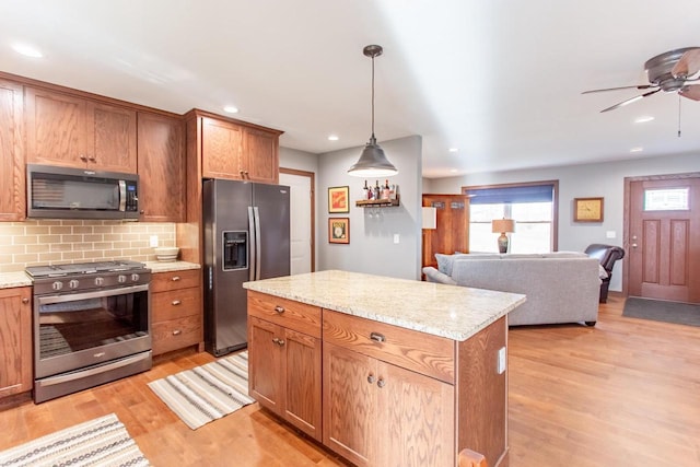 kitchen featuring decorative backsplash, stainless steel appliances, decorative light fixtures, light hardwood / wood-style flooring, and a kitchen island