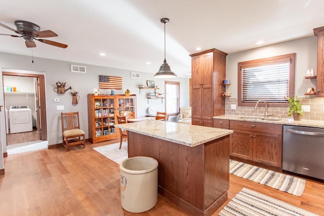 kitchen featuring sink, hanging light fixtures, stainless steel dishwasher, backsplash, and washer / dryer