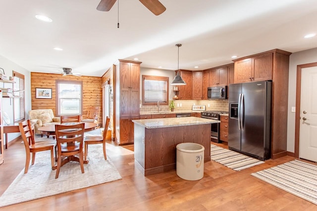 kitchen with rustic walls, stainless steel appliances, sink, decorative light fixtures, and a kitchen island