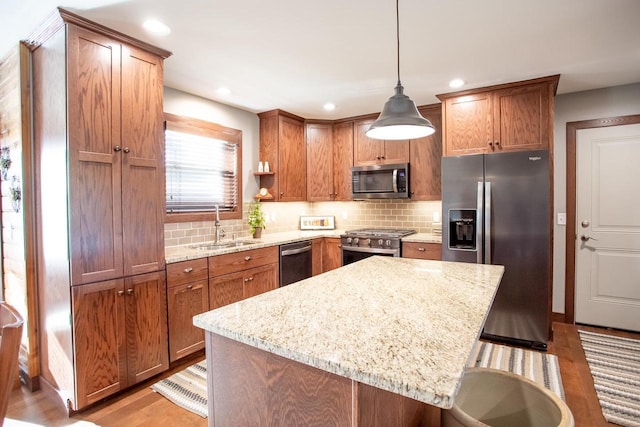 kitchen with light stone countertops, a kitchen breakfast bar, stainless steel appliances, sink, and pendant lighting