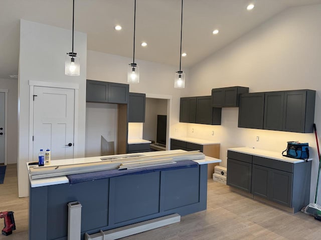 kitchen featuring high vaulted ceiling, pendant lighting, light wood-type flooring, and a kitchen island