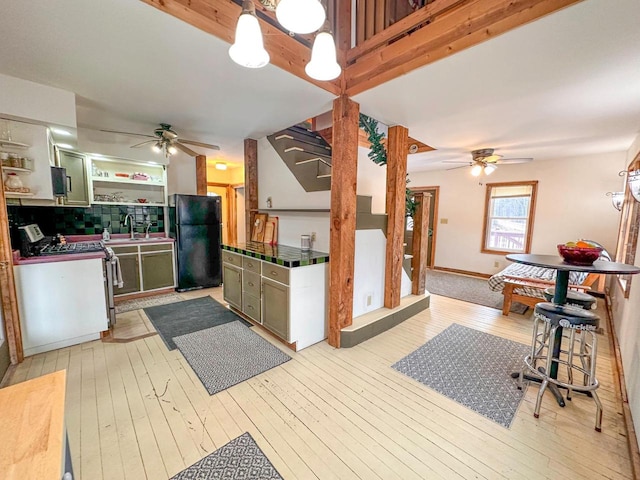 kitchen featuring green cabinets, black fridge, white range, and tasteful backsplash