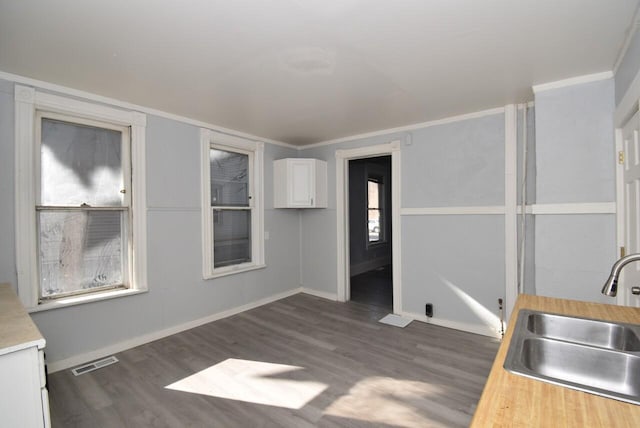 kitchen featuring white cabinets, crown molding, dark hardwood / wood-style flooring, and sink