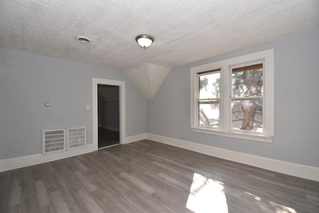 additional living space featuring a textured ceiling, dark hardwood / wood-style floors, and lofted ceiling