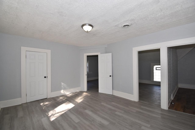 unfurnished bedroom with a textured ceiling and dark hardwood / wood-style floors