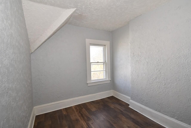 additional living space featuring lofted ceiling, a textured ceiling, and dark wood-type flooring