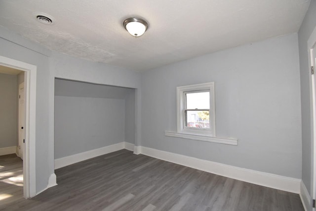 empty room featuring dark hardwood / wood-style flooring and a textured ceiling