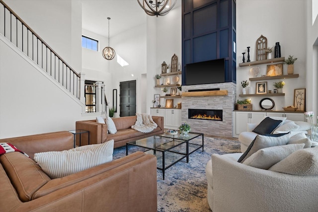 living room with a notable chandelier, a tile fireplace, and a high ceiling