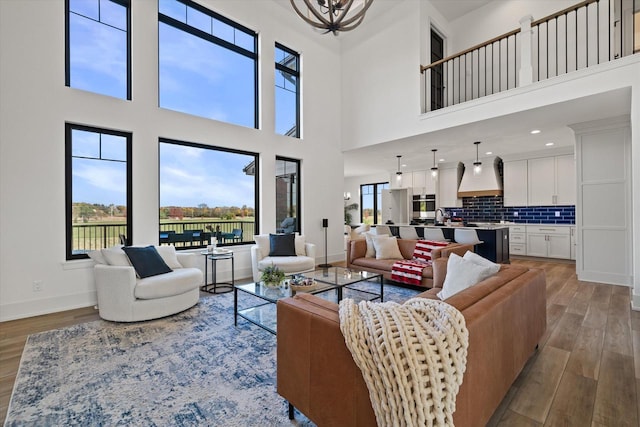 living room with a towering ceiling, sink, and light hardwood / wood-style flooring