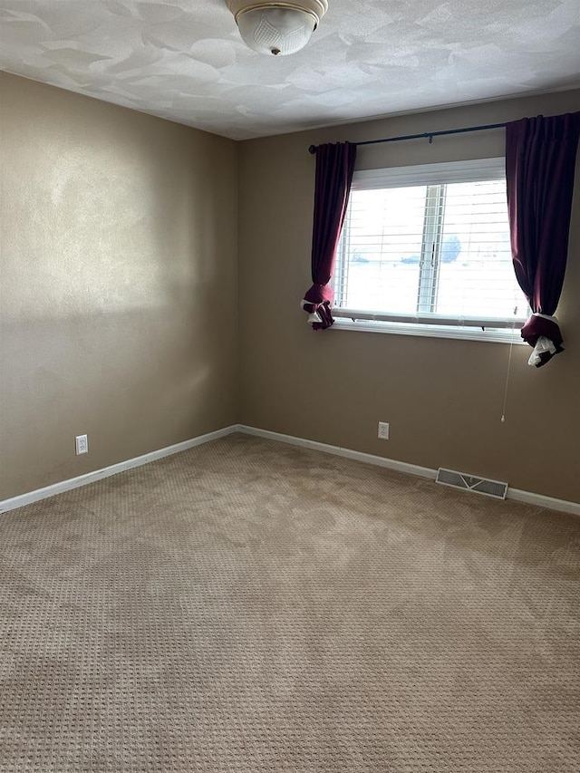 carpeted empty room featuring a textured ceiling