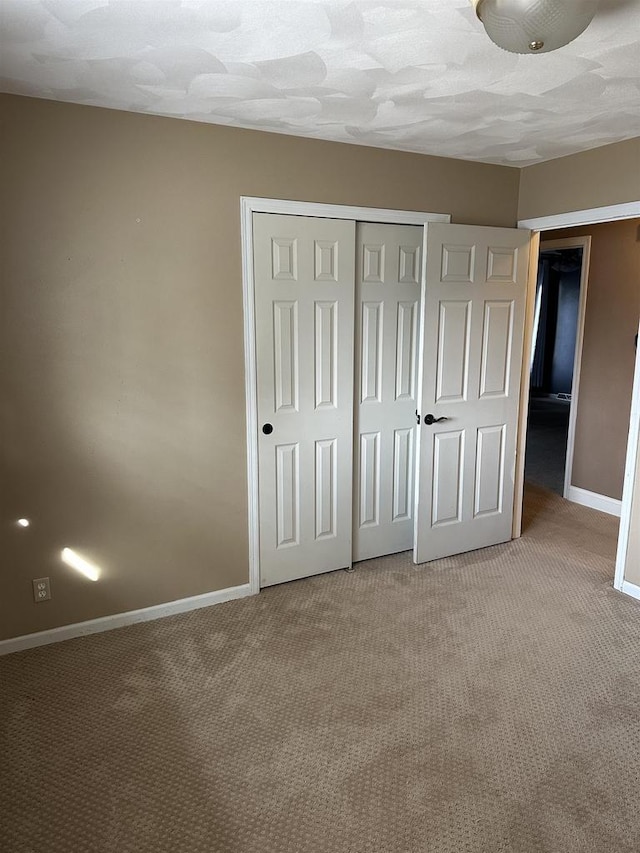 unfurnished bedroom with a closet and light colored carpet