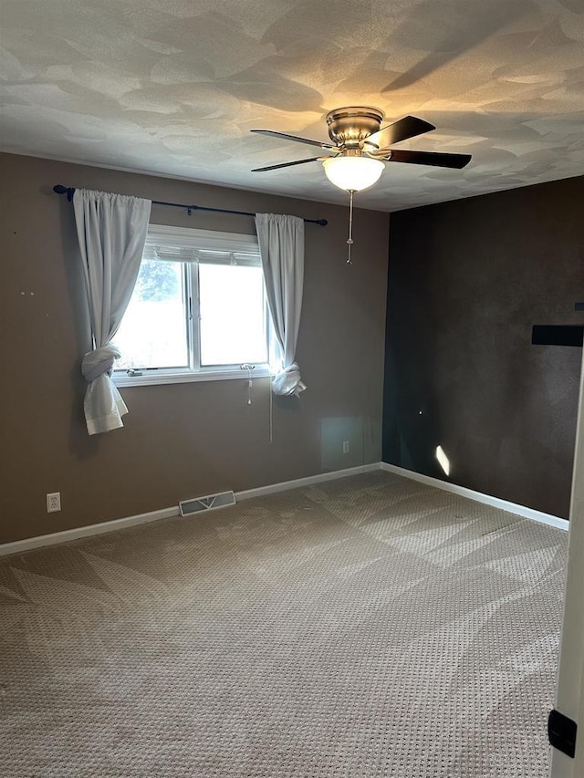 carpeted spare room featuring a textured ceiling and ceiling fan