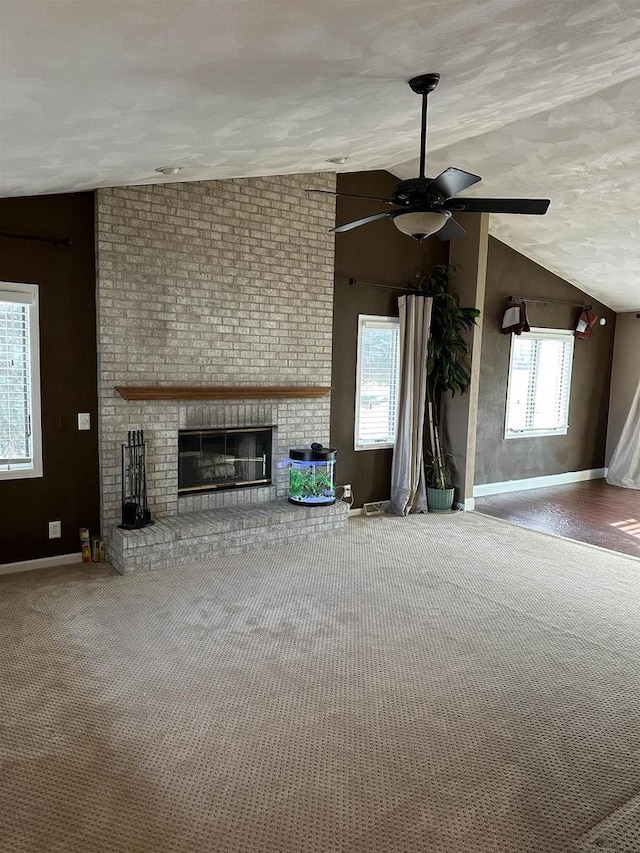 unfurnished living room featuring a fireplace, vaulted ceiling, and plenty of natural light