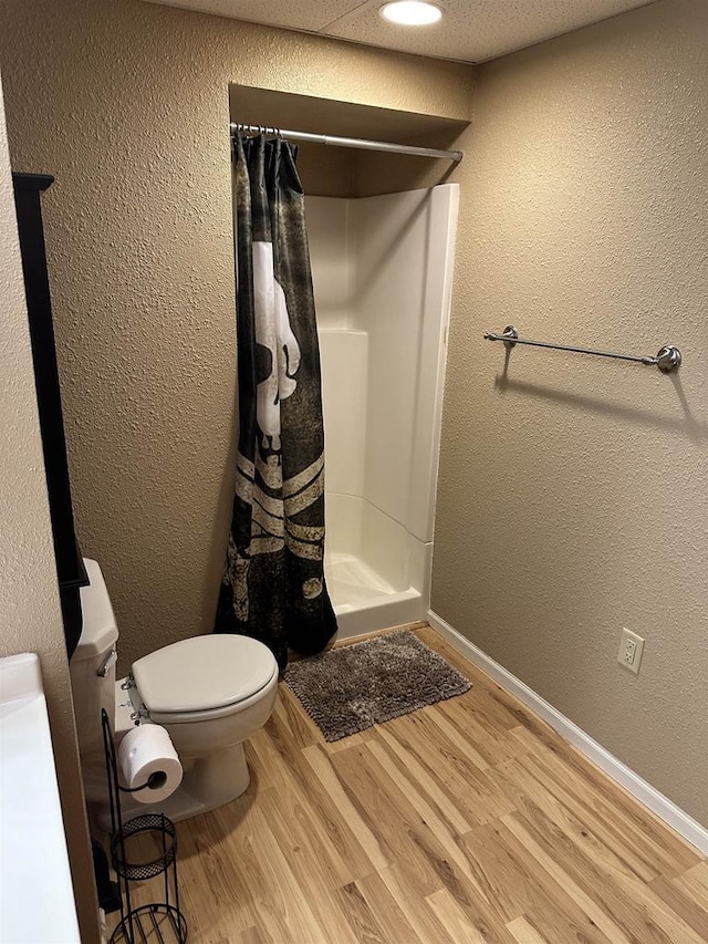 bathroom featuring toilet, wood-type flooring, and walk in shower