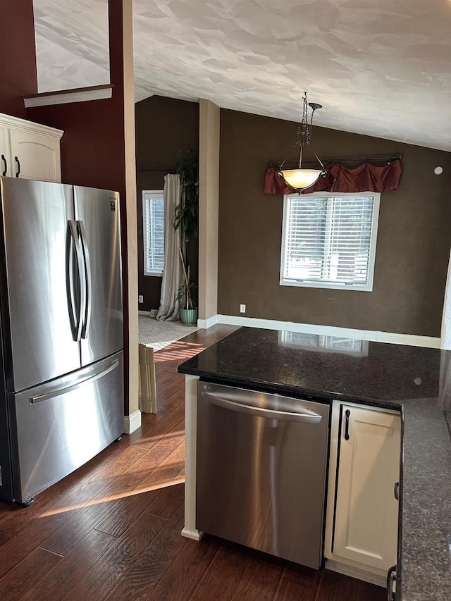 kitchen with pendant lighting, vaulted ceiling, appliances with stainless steel finishes, dark hardwood / wood-style flooring, and white cabinetry