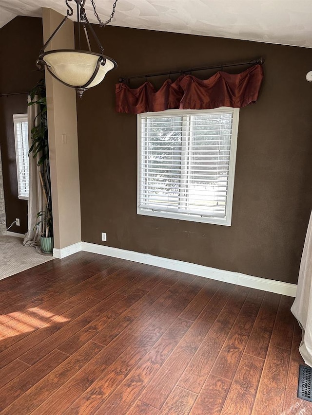 unfurnished dining area with vaulted ceiling and dark wood-type flooring