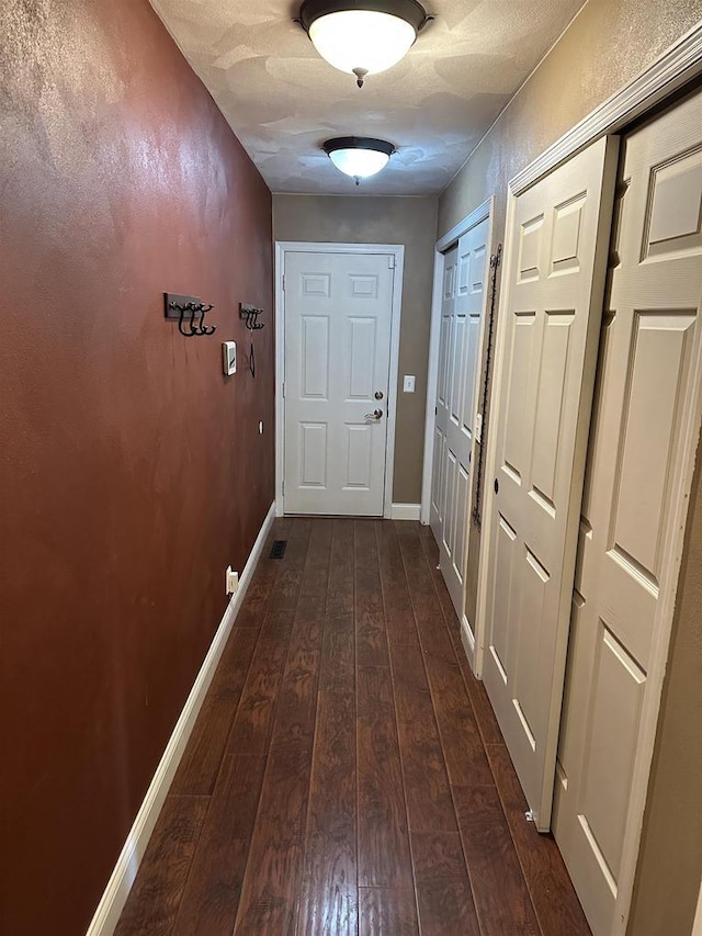 corridor featuring dark hardwood / wood-style floors and a textured ceiling