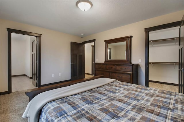 carpeted bedroom featuring a closet, a walk in closet, and baseboards