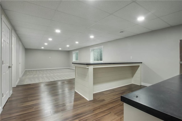 bar with dark wood-style floors, a drop ceiling, recessed lighting, and baseboards