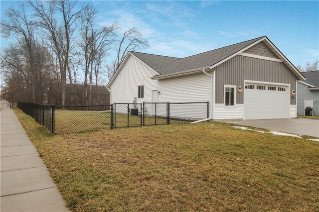 view of side of property with a gate, fence, driveway, a garage, and a lawn