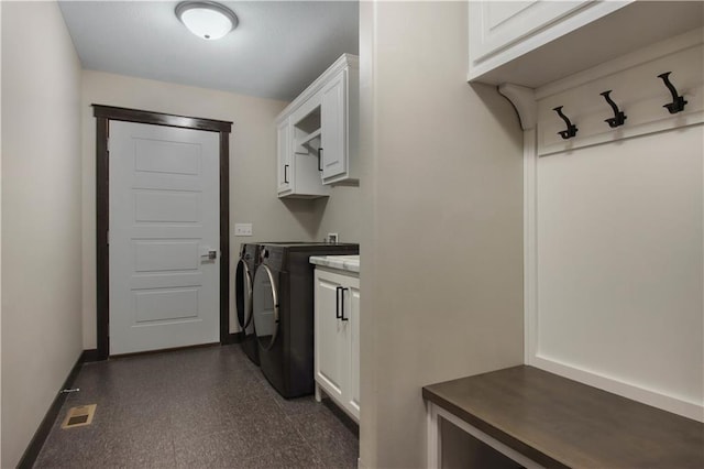 clothes washing area featuring visible vents, baseboards, dark floors, washer and dryer, and cabinet space